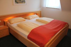 - une chambre avec un lit et une couverture rouge dans l'établissement Gästehaus zum Landesteg, à Immenstaad am Bodensee