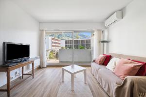 a living room with a couch and a tv at ROCAMARE Piscine toit terrasse - Parking privée - Terrasse in Menton