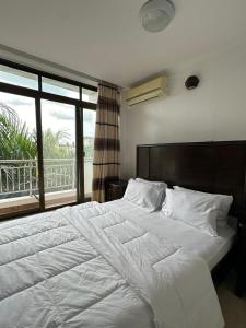 a bedroom with a large white bed with a window at Secluded-Loft-2 BEDROOM-2-Bath in Dar es Salaam