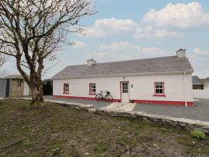 a white house with a tree in front of it at Teach Phaidí Mhóir in Donegal