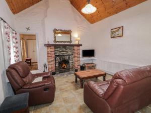 a living room with leather furniture and a fireplace at Teach Phaidí Mhóir in Donegal