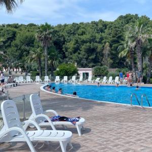 una persona tumbada en un sillón junto a una piscina en Villaggio La Giara, en Vieste