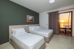 two beds in a room with a view of the ocean at Hotel Idi in Vlorë
