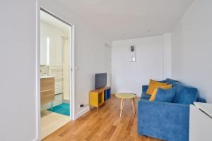 ein Wohnzimmer mit einem blauen Sofa und einem Spiegel in der Unterkunft Appartement calme vue Château in Versailles