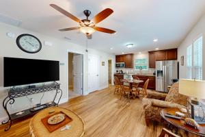 a living room with a ceiling fan and a tv at Charming apartment with beautiful marsh views and shared patio in Fernandina Beach