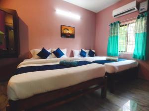 two beds in a room with green curtains at Gratitude Retreat in Puducherry
