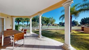 un porche avec des colonnes blanches et une table en bois dans l'établissement Greenview Villa by ON Travel, à Oliva