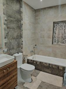 een badkamer met een toilet, een bad en een wastafel bij Star Dream Apartment in Xgħajra