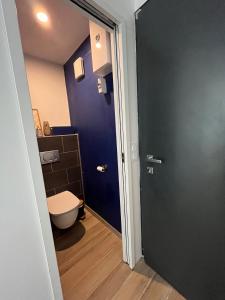 a bathroom with a toilet and a blue door at En bord de mer, vue et accès direct à la plage in Batz-sur-Mer
