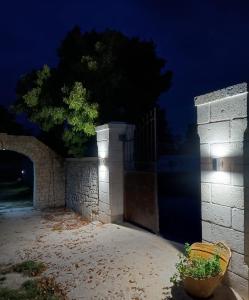 a stone wall with a gate and a tree at night at Tenuta I Quattro Venti in Otranto