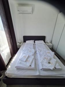 Ce lit se trouve dans un dortoir doté de draps et d'oreillers blancs. dans l'établissement DELUXE Beach Apartment in Sveti Vlas, à Sveti Vlas