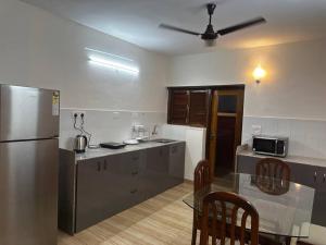 a kitchen with a stainless steel refrigerator and a table at Pixels Luxury Modern Apartment 5 Min to Palolem Beach in Canacona