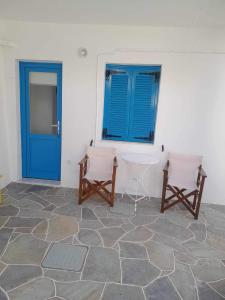 Pokój z 2 krzesłami i niebieskimi drzwiami w obiekcie Kouki Maria Rooms w mieście Apollonia