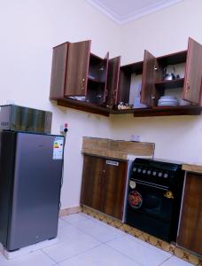 een keuken met een zwarte koelkast en houten kasten bij Ahva II Residence in Jinja