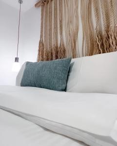 a white bed with a blue pillow on it at Sabbia By LD Hoteles in El Roque
