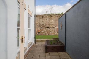 an alley between two buildings with a stone wall at Sheriffs Tower Cottage - East in Bishop Auckland