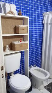 baño con aseo y pared de azulejos azules en Cabaña,Chalet Alpino Bosques de Peralta Ramos en Mar del Plata