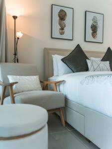 a bedroom with a white bed and a chair at Gorgeous Apt Studio with balcony in Business Bay in Dubai
