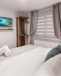 a bedroom with two beds and a window with a tv at Sabbia By LD Hoteles in El Roque