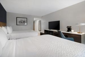 a hotel room with two beds and a flat screen tv at Best Western Plus Meadowlands in Secaucus