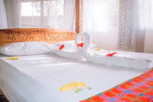 dois cisnes feitos de toalhas sentadas numa cama em Kijani Cottages - In Diani em Praia de Diani
