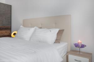 1 cama con almohadas blancas y una vela sobre una mesa en VIVERIA en Oradea