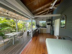 une terrasse couverte avec une table et des chaises ainsi qu'une cuisine dans l'établissement Très joli bungalow et sa petite piscine privee, à Rivière-Salée