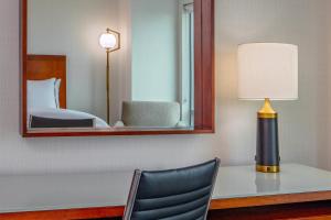 um quarto com uma secretária com um candeeiro e um espelho em The Westin Boston Seaport District em Boston