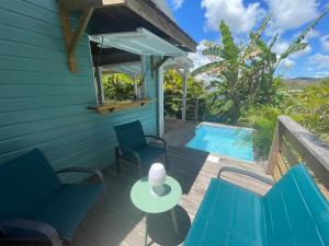 une terrasse avec des chaises bleues et une piscine dans l'établissement Très joli bungalow et sa petite piscine privee, à Rivière-Salée