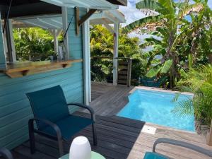 une terrasse avec une chaise et une piscine dans l'établissement Très joli bungalow et sa petite piscine privee, à Rivière-Salée