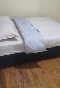 ein Bett mit weißer Bettwäsche und Kissen auf einem Holzboden in der Unterkunft Heights View in Lautoka