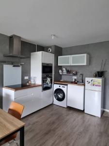 una cucina con elettrodomestici bianchi e pavimenti in legno di Appartement en résidence - Trappes a Trappes