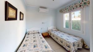 two beds in a room with two windows at Villa Cisne by ON Travel in Casas Devesa