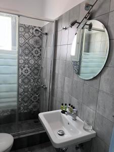 ein Bad mit einem Waschbecken, einem Spiegel und einer Dusche in der Unterkunft Captain's Studios in Spetses