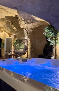 a pool of blue water in a room with a stone wall at Hôtel-Restaurant-Chambre Insolite Spa - Le XII de Luynes in Luynes