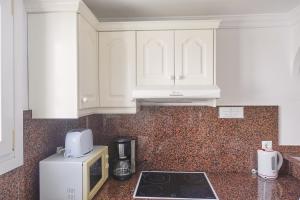 a kitchen with white cabinets and a microwave at Peony by ON Travel in Oliva