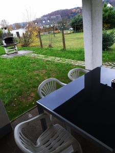 een zwarte tafel en twee witte stoelen op een veranda bij TBM Haus in Homburg