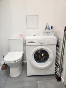 a bathroom with a washing machine and a toilet at T1Bis centre ville avec Patio in Saint-Jean-dʼAngély