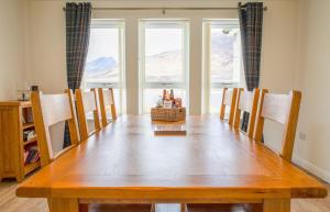 a dining room table with chairs and a large window at Taigh Cill Chriosd in Kilbride