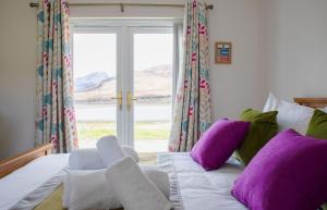 a bed with purple and white pillows and a window at Taigh Cill Chriosd in Kilbride