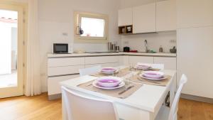 a white kitchen with a table with pink dishes on it at Sardinianworld - Casa Sofia in Oristano