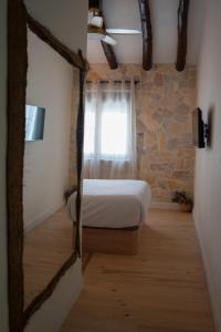 1 dormitorio con cama y pared de piedra en Estancia dos Olivos, en Quesa