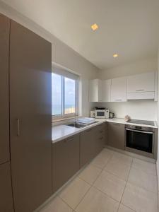 eine Küche mit weißen Schränken und einem großen Fenster in der Unterkunft Spectacular Distant Seaview Apt in Sliema