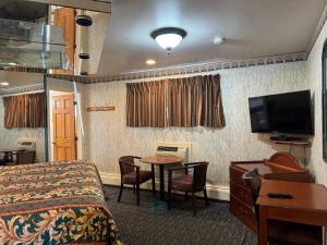 Cette chambre comprend un lit, une table et une télévision. dans l'établissement Royal Motel, à Secaucus