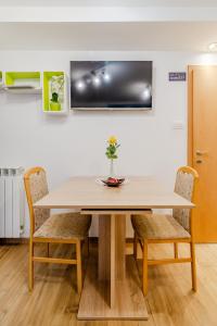 a dining room table with chairs and a tv on the wall at Apartmaji Hosnar in Bovec