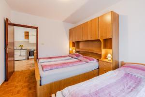 two beds in a bedroom with wooden cabinets at Apartmaji Hosnar in Bovec