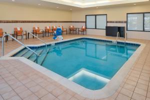 - une piscine dans une chambre d'hôtel avec des chaises et des tables dans l'établissement Courtyard by Marriott Milwaukee North/Brown Deer, à Brown Deer