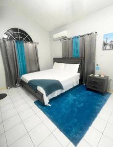 a bedroom with a bed and a blue rug at Cozy Elegance 3 Bedroom Estate in Portmore