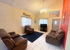 a living room with two couches and a television at Cozy Elegance 3 Bedroom Estate in Portmore