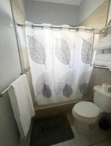 a bathroom with a toilet and a shower curtain with umbrellas at Cozy Elegance 3 Bedroom Estate in Portmore